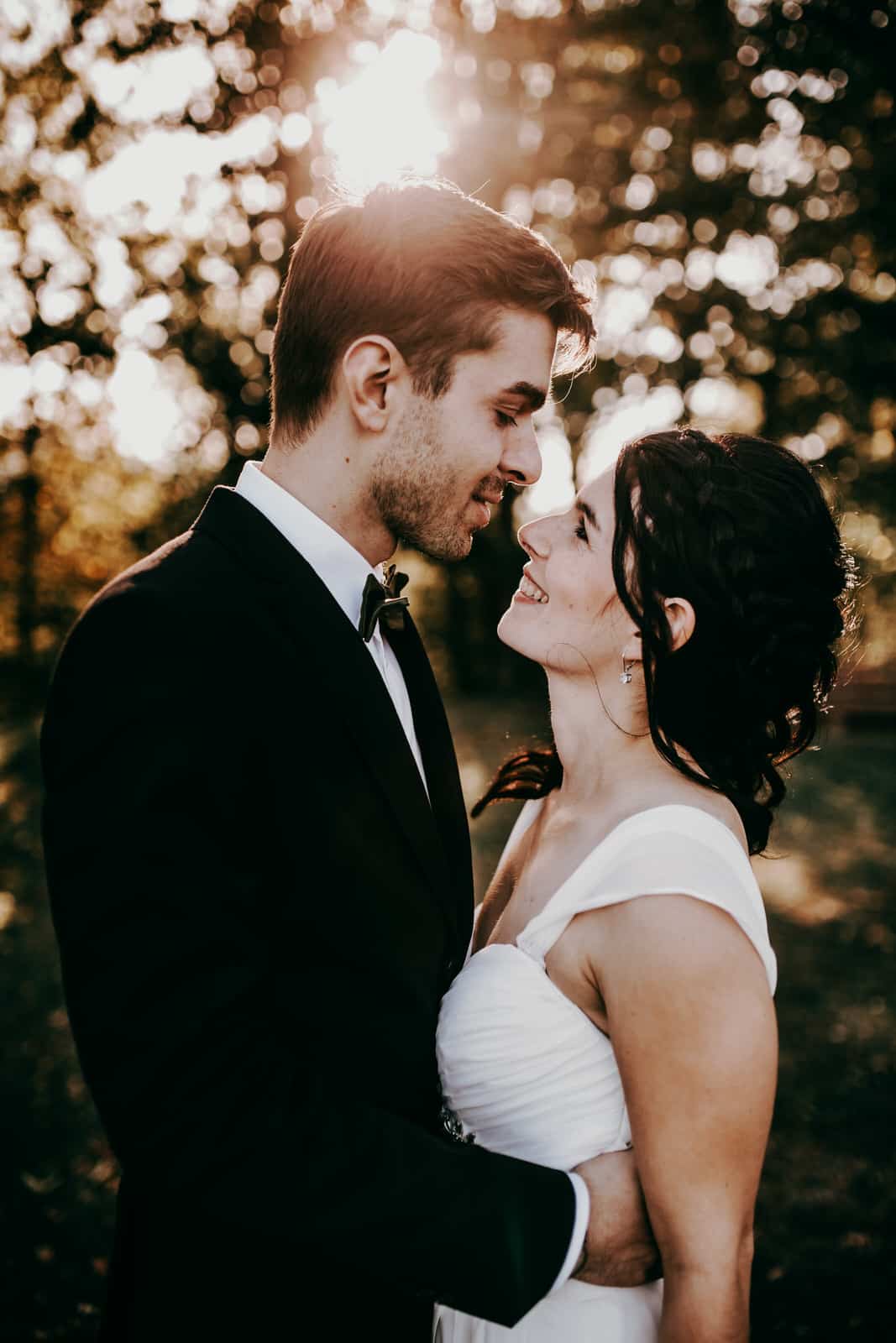 Als Hochzeitsfotografen lieben wir warmes natürliches Licht. SO wie hier auf diesem Bild. Es sind nur die Köpfe und ein Teil des Oberkörpers des Brautpaares zu sehen. Braut und Bräutigam sehen sich verliebt an.